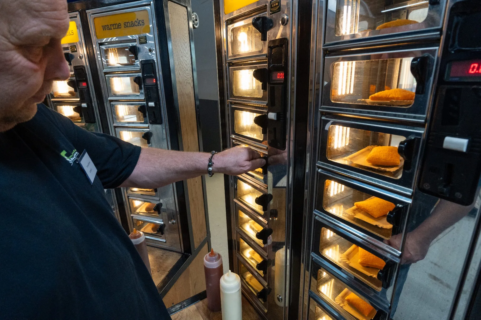 Medewerker pakt een warme snack uit de snackmuur tijdens het jubileum