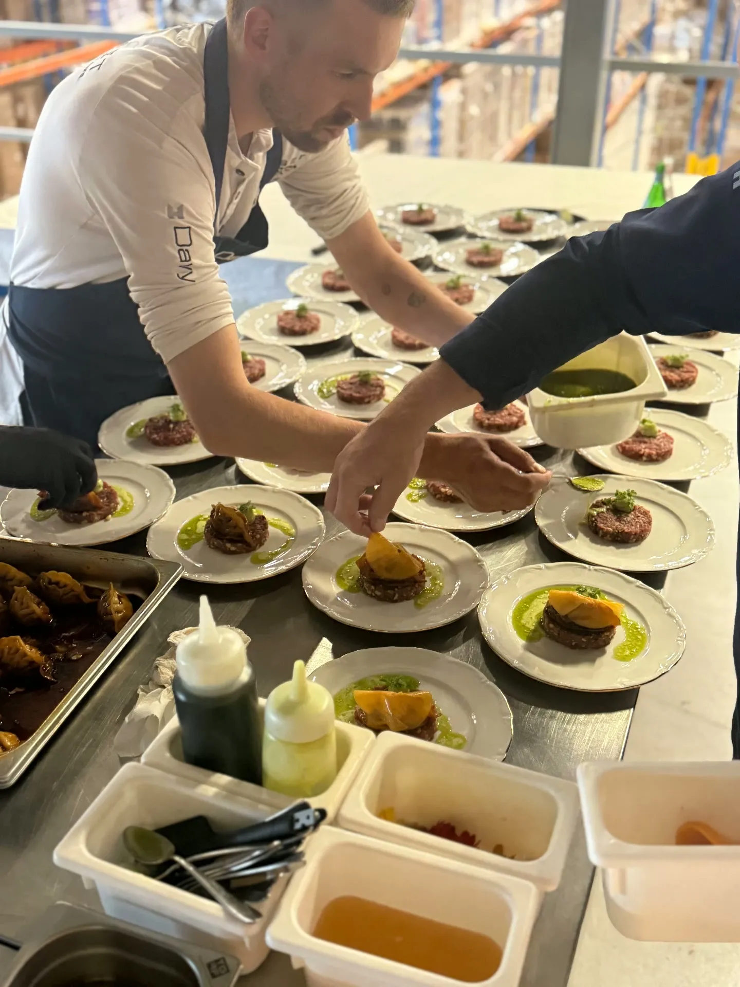 Chef die gerechten aanricht op een stalen tafel in de hal